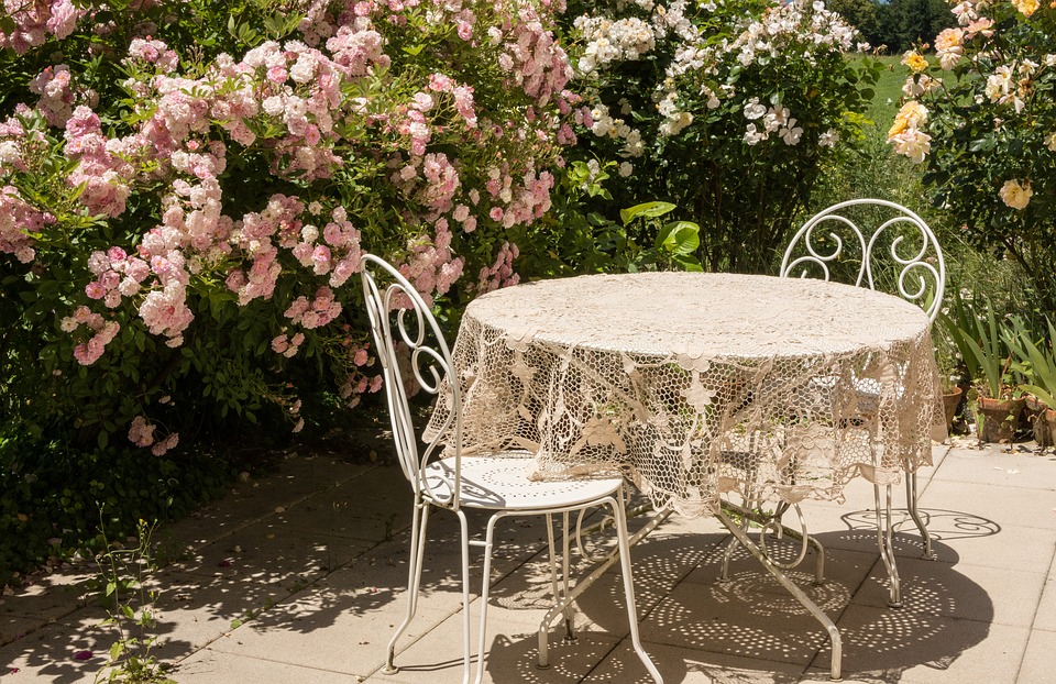 Hyggelig terrasse med bord, stole og blomster